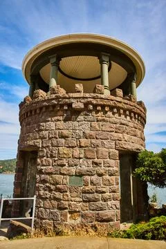Lyfords Stone Tower under cloudy blue sky framed by ocean and distant shore 写真素材