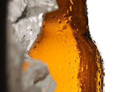 Lying bottle of ale on ice cubes. Close up. White background Stock Photos
