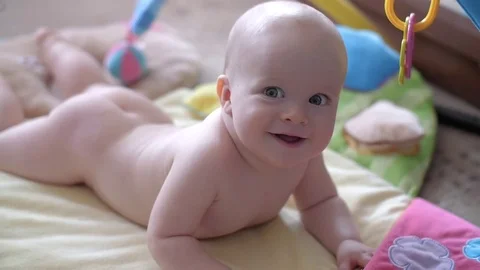Lying on a children's rug kid cheerfully smiling and looking at the camera 動画素材 80325436