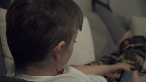 Lying on the couch, a student plays a game on his smartphone. Children's depende Stock Footage 146316414