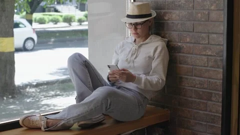 Lying down on windowsill woman using phone to chat with friends. Chatting with Stock Footage 277772726