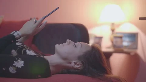 Lying down, woman relaxing on couch indoors, using phone Stock Footage 333069074