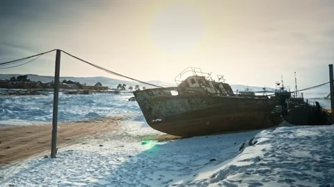Lying on its side is a dead, rusty ghost ship. Winter, the shore, houses are Stock Footage 257764661