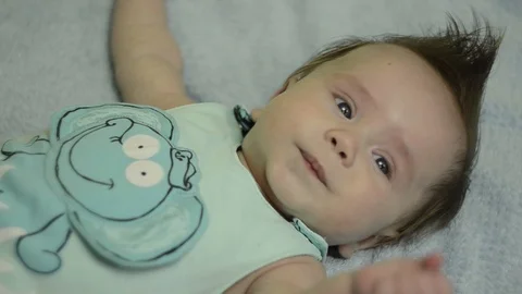 Lying toddler boy pulls his hand to mouth - 3 month old baby Stock Footage 114968154