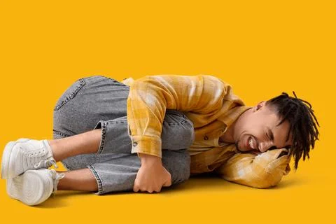 Lying young man having panic attack on yellow background Stock Photos
