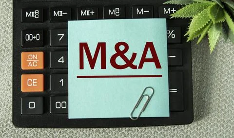 M and A - acronym on the note sheet on the background of the calculator Stock Photos