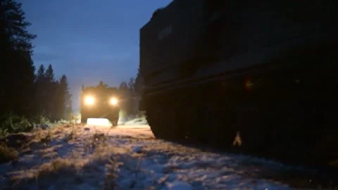 An M270 multiple launch rocket system travelling on snow covered track at night Video stock 292778349