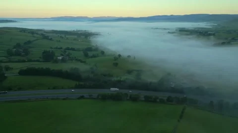 M6 motorway, green patchwork fields, fog bank and distant mountains at Video stock 248495017