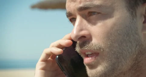 Ma talks to his mobile on the beach Stock Footage 205022900