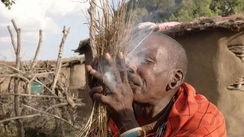 A maasai warrior starts fire the traditional way at a manyatta in kenya Stock Footage