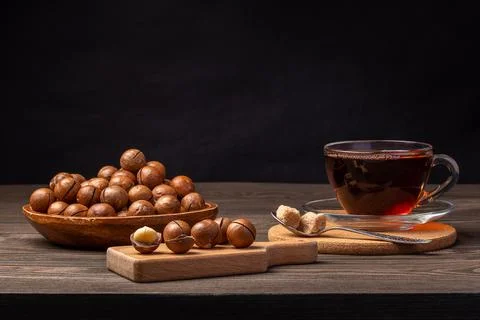 Macadamia nuts and a cup of tea on a wooden table Stock Photos