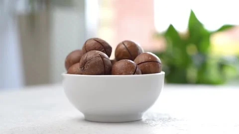 Macadamia nuts in a bowl are spinning on the table. The camera moves around. Stock Footage 161296012
