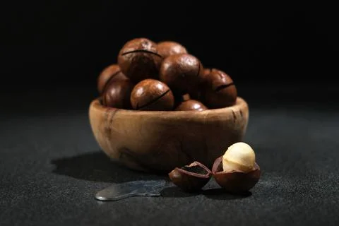 Macadamia nuts with a key on black background. Stock Photos