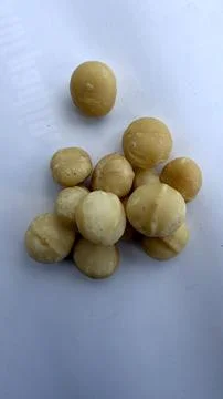 Macadamia nuts pile on white background for premium food and healthy snack use Stock Photos