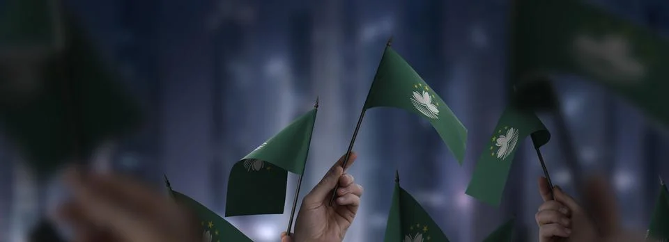 Macao flags in their hands on a blurred urban background Stock Photos