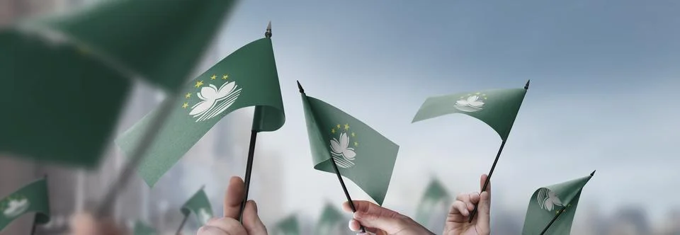 Macao flags in their hands on a blurred urban background Stock Photos