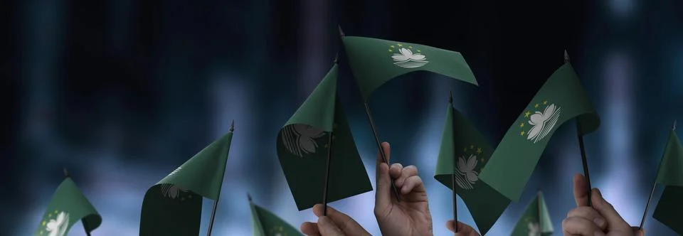 Macao flags in their hands on a blurred urban background Stock Photos