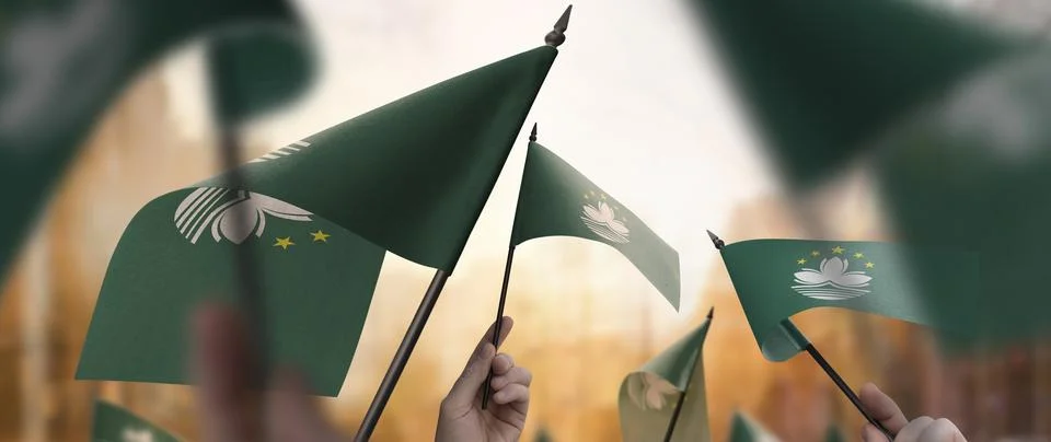 Macao flags in their hands on a blurred urban background Stock Photos