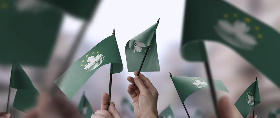 Macao flags in their hands on a blurred urban background Stock Photos