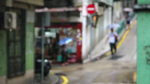 Macao - People with umbrellas walking in small charming street. Defocused look. Stock Footage 70532176