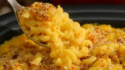 Macaroni and cheese. Spoon scooping through bubbling breadcrumb crust. CU Stock Footage 102136073