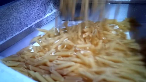 Macaroni falling down in a la carte machine on a conveyor belt Stock Footage 154347997