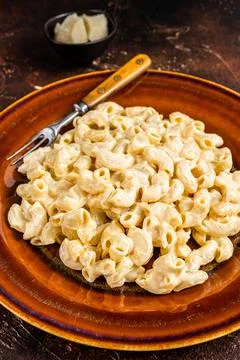 Macaroni Mac and cheese with Cheddar sauce in a plate. Dark background. Top view Stock Photos