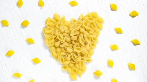 Macaroni on a white background in the shape of a heart. Love of pasta. Stock Photos