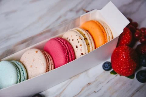 Macaronis in a white box with a transparent window. Color dessert, pink, mi.. Stock Photos