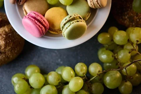 Macarons and grapes on rustic tabletop bright candy colors food still life Stock Photos