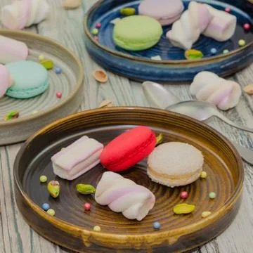 Macarons and marshmallows on plates Stock Photos
