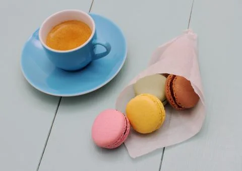 Macarons in backing paper cornet and blue espresso cup Stock Photos