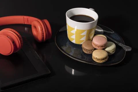 Macarons with coffee cup and technology on a black background. Stock Photos