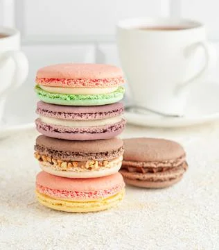 Macaroons are stacked. In the background, a cup with coffee. Light background Stock Photos