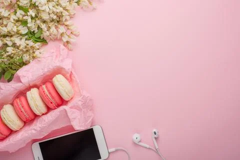 Macaroons in a box on a light pink background with a phone, flatlays, with em Stock Photos