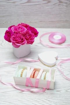 Macaroons in the box as present. Spring banner with pink roses bouquet Stock Photos