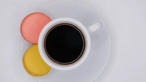 Macaroons with coffee in white cup are rotating on white background. Top view. Stock Footage 106984491