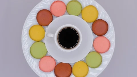 Macaroons with coffee in white cup are rotating on white plate. Top view. Stock Footage 106984809