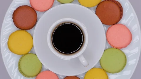 Macaroons with coffee in white cup are rotating on white plate. Top view. Stock Footage 107185445