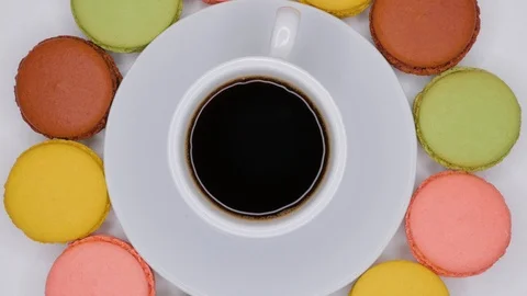 Macaroons with coffee in white cup are rotating on white plate. Top view. Stock Footage 107412838