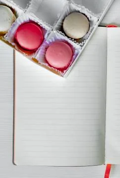Macaroons cookies on the table next to an open notebook and pen. view from above Stock Photos