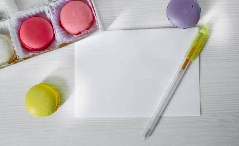 Macaroons cookies on a table next to a postcard and pen. view from above. Fotos Stock