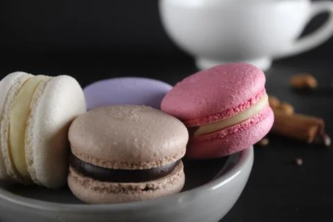 Macaroons on a gray plate at the back stands a cup of coffee or tea coffee be Stock Photos
