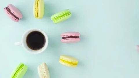 Macaroons or macaron on pastel blue surface with espresso in white cup. Vídeo Stock 130940294
