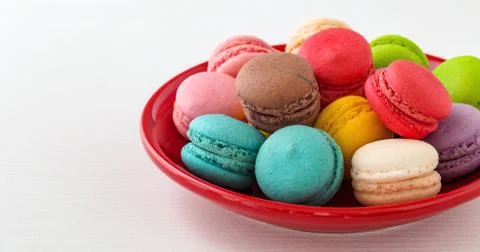 Macaroons on red plate on white table Stock Photos