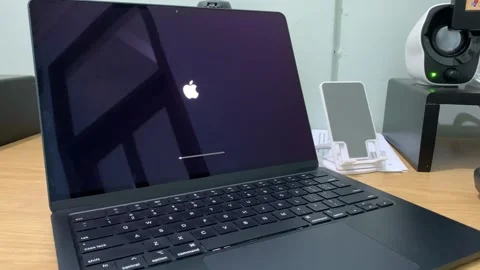 A MacBook screen displaying a system update progress bar during the macOS Stock Footage 312026782