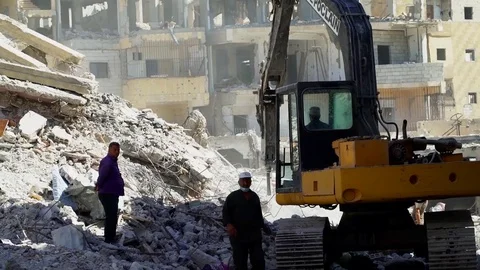 Machine and engineers work to clear rubble from streets of Raqqah, Syria Stock Footage 94565394