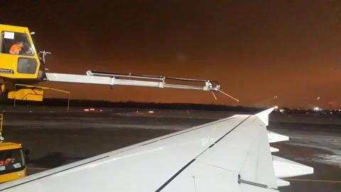 Machine and technician de-icing the wing of an aircraft at night. Stock Footage 296343656