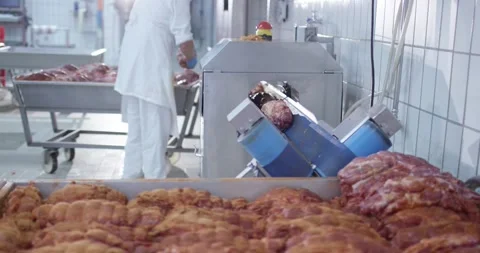 Machine with blue rollers transporting pieces of raw meat in a tiled meat Stock Footage 339989682
