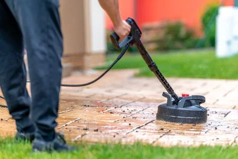 Machine cleaning stone pavement in front of the house with a brush Stock Photos